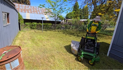 Uniformed lawn care technician operating a stand-on mower in a backyard