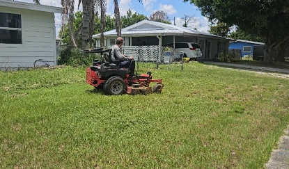 Lawn care crew member mowing a residential yard with a zero-turn mower