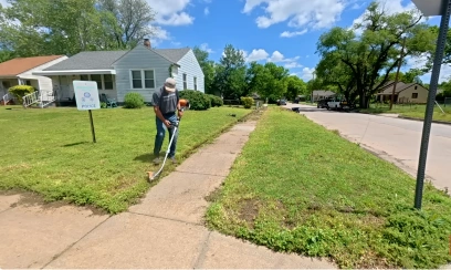 Lawn care technician edging the sidewalk along a front yard in Katy, TX